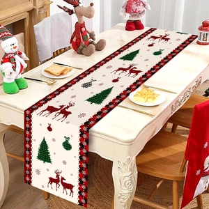 Christmas table runner with reindeer and tree patterns on a rustic wooden dining table