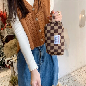 Gros plan sur la trousse à maquillage en velours côtelé marron à carreaux avec poignée