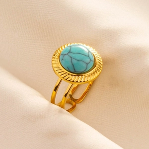 Detailansicht eines goldfarbenen Edelstahlrings mit rundem blauem Türkisstein-Inlay