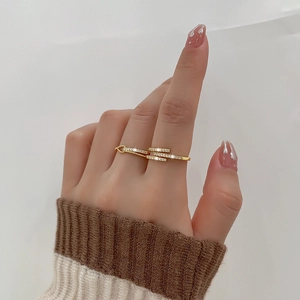 Golden criss-cross knot ring featuring multi-row pave zircons on woman's finger