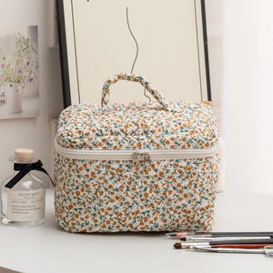 Detailed close-up of quilted floral makeup bag with dual zippers and cream cotton texture
