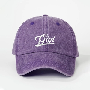 Detailed close-up of white Gigi embroidery on a purple washed vintage denim baseball cap