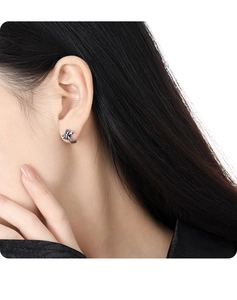 Close-up of S925 sterling silver vintage crown cross earrings worn on a female ear model