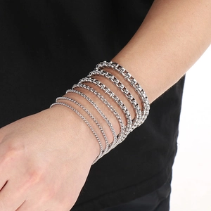 Detail view of various thickness silver box chain bracelets showing different widths on wrist