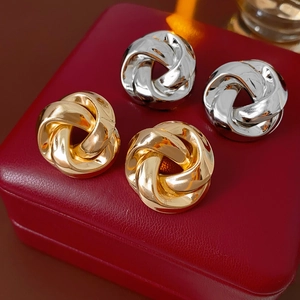 Détail de boucles d'oreilles nœuds métalliques dorées et argentées sur cuir rouge