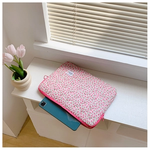 Detail view of pink floral laptop sleeve with a zipper on a bright sunny windowsill