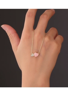 Detail of a gold double heart pendant necklace with pink stone and zircon on a gold chain