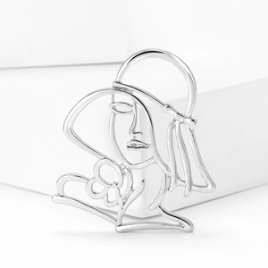 Detail shot of silver alloy cutout brooch with abstract line art face and floral motif