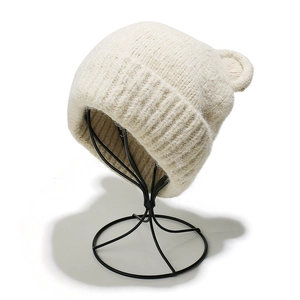 Dettaglio della trama a maglia del cappello crema con orecchie d'orso e maglia a coste