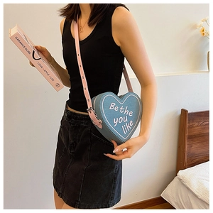 Détail du sac bandoulière en denim en forme de cœur avec broderie rose et sangle