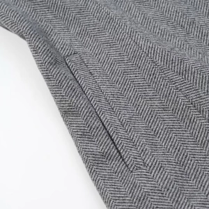 Macro du tissu gris à chevrons et détails de couture sur la poche d'un ensemble de costume A-line