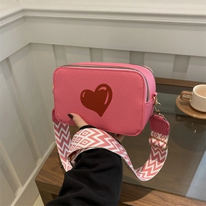 Pink crossbody camera bag with red heart and geometric pattern wide shoulder strap