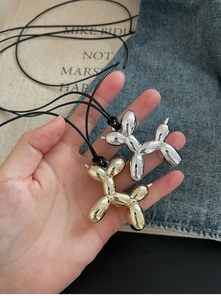 Handheld shot of metallic gold and silver balloon dog pendants on black cords