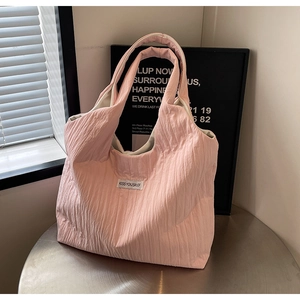 Rosa Faltenstoff-Tasche mit KISS YOURSELF Label auf einem Metall-Cafétisch
