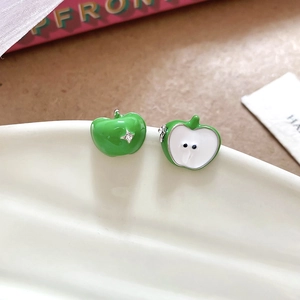 Detailed close-up of green apple stud earrings with rhinestone on a white ceramic plate