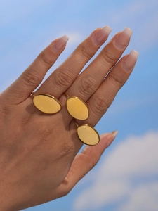 Low angle view of gold oval textured ring against blue sky showing aesthetic geometric design