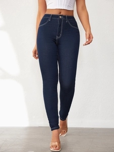 Detail view of high waist skinny jeans with contrast white stitching and dark blue denim fabric