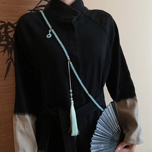 Pale blue beaded crossbody chain with tassel on black traditional Chinese dress
