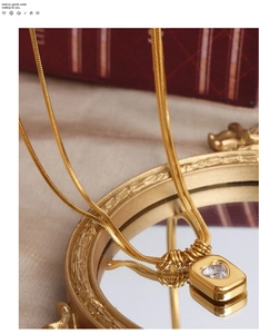 Detail of gold layered snake chain necklace with heart zircon pendant on mirror