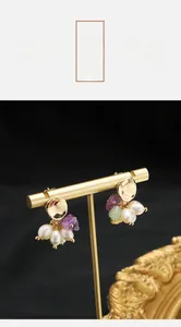 Detail of handmade natural pearl earrings with gold plating and vintage stone accents