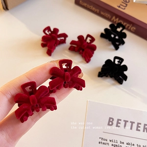 Close-up of small red and black velvet bow hair clips held in hand for hair styling