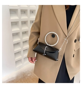 Detail of black crossbody bag featuring a rhinestone-encrusted ring handle and metal chain