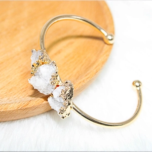 Macro view of white druzy crystal clusters on a gold-plated adjustable open cuff bracelet