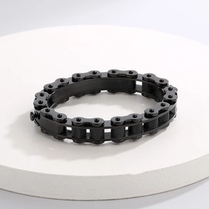 Industrial black chain bracelet on a white stone pedestal with sharp mechanical detail