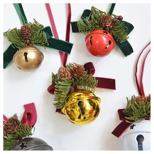 Detail of Christmas bell ornaments featuring velvet ribbons, pine cones, and red berries