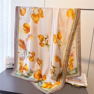 Detail of silk-like floral scarf with ivory base and orange flowers draped on a metal rack