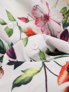 Vue détaillée de l'imprimé floral coloré sur popeline avec détail de bouton blanc