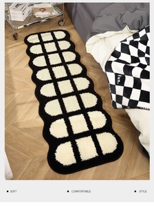 Dettaglio del tappeto peluche a scacchi bianco e nero con bordi ondulati su legno