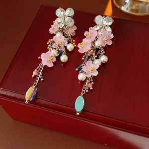 Vista macro di orecchini vintage con fiori rosa e perle su sfondo di legno scuro
