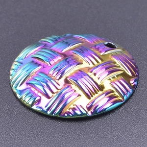 Detail of round stainless steel pendant with embossed woven texture and rainbow plating