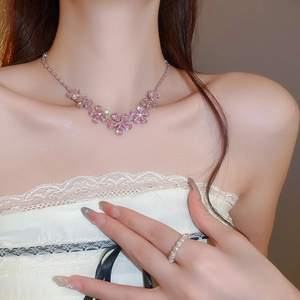 Close-up of pink zircon flower pendant necklace and pearl ring worn by a female model