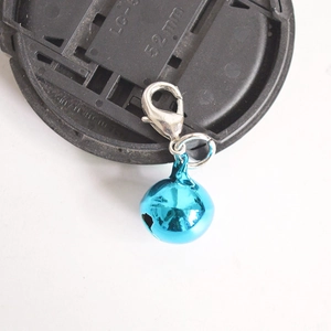 Detail of a bright blue metal bell pendant featuring a silver lobster clasp for keychains