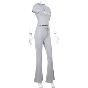 Detailansicht des grauen Zweiteilers mit bauchfreiem Grafik-Top und ausgestellter Hose