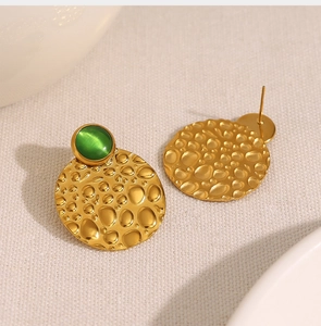 Detail of gold hammered texture stud earrings featuring a round green cat eye stone inlay
