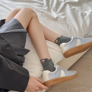 Detail of baby blue sneakers with brown gum soles and grey bow socks in a cozy setting