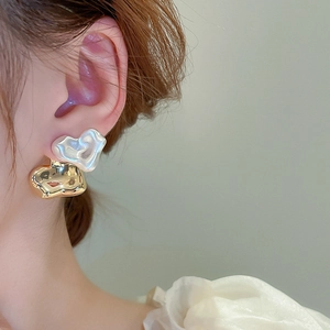 Close-up of elegant irregular heart earrings with gold plating and pearl inlay on model