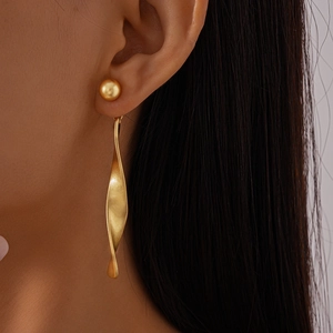 Close-up of gold twisted metal dangle earrings with imitation pearls on female model