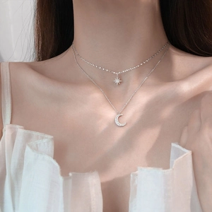 Elegant silver layered necklace with star and moon charms on a model's neck