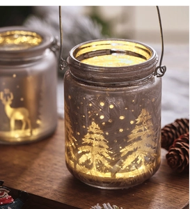 Frosted glass Christmas jar light with golden deer and warm LED glow on wood