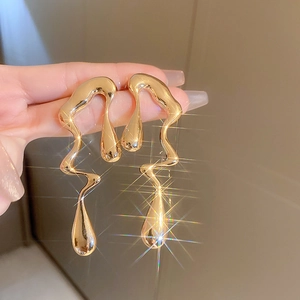 Macro shot of liquid metal earrings in gold with irregular molten teardrop design