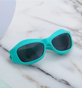 Detail of Y2K teal cycling sunglasses with matte frame and dark grey lenses on marble