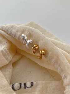 Detailed close-up of textured gold and silver metal stud earrings on a linen bag