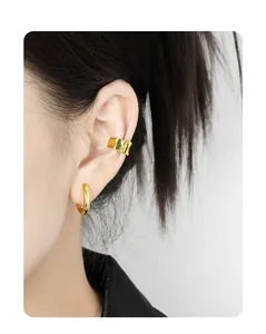 Close-up of elegant gold S925 sterling silver hoop earrings and ear cuff on model ear