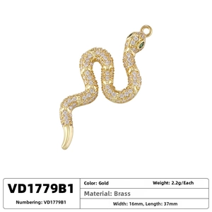 Macro detail of gold plated snake pendant with white zircon pavé and green gem eyes
