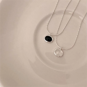 Detailed close-up of oval black onyx and white shell necklaces on a ceramic plate