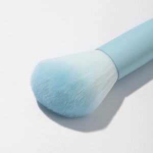 Detailed close-up of soft light blue makeup brush bristles and ergonomic handle